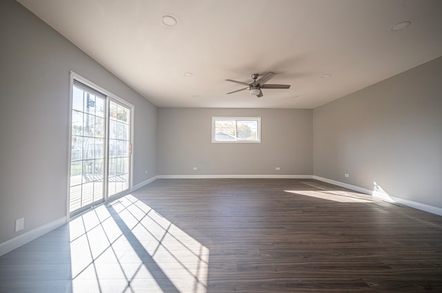 spare room with a wealth of natural light, dark wood-type flooring, and ceiling fan