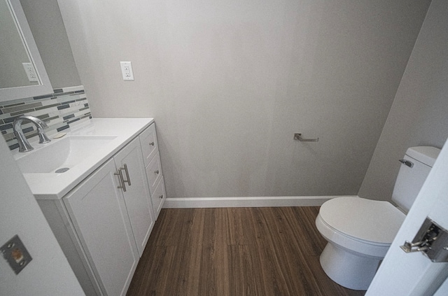 bathroom with vanity, wood-type flooring, toilet, and tasteful backsplash