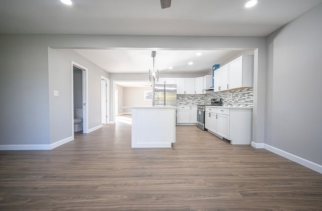 kitchen with dark hardwood / wood-style floors, stainless steel stove, a center island, pendant lighting, and white cabinets