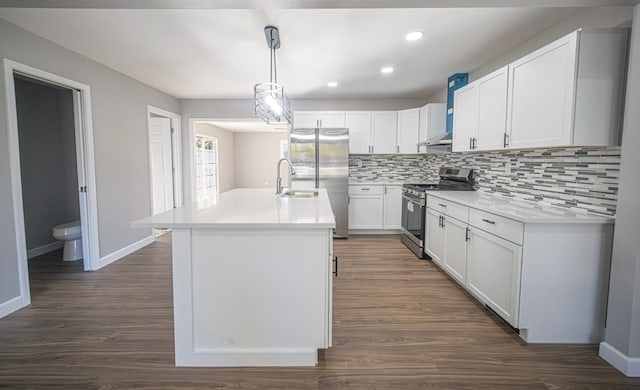 kitchen with a kitchen island with sink, dark hardwood / wood-style floors, stainless steel appliances, decorative light fixtures, and white cabinets