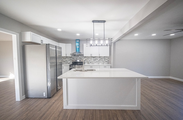 kitchen featuring wall chimney range hood, an island with sink, appliances with stainless steel finishes, dark hardwood / wood-style floors, and sink