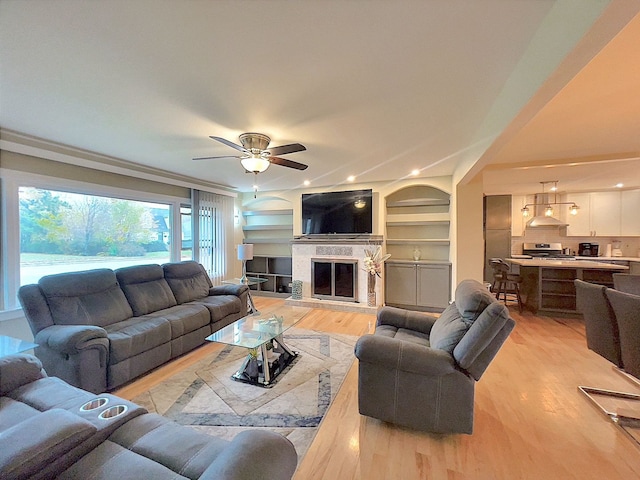 living room featuring ceiling fan, light hardwood / wood-style floors, and built in features