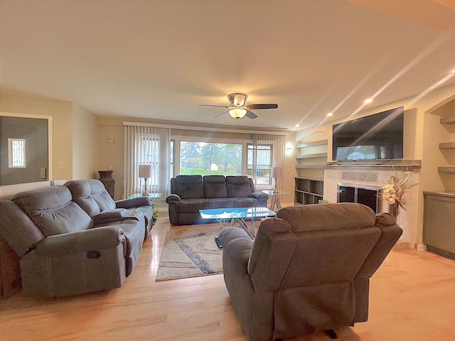 living room with light hardwood / wood-style flooring, ceiling fan, and built in features