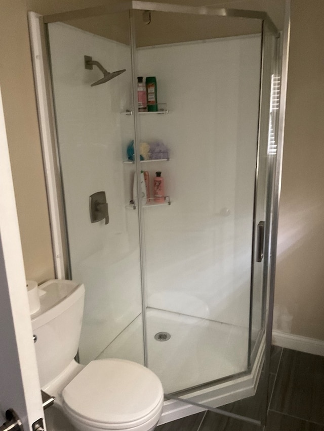 bathroom with toilet, walk in shower, and hardwood / wood-style floors