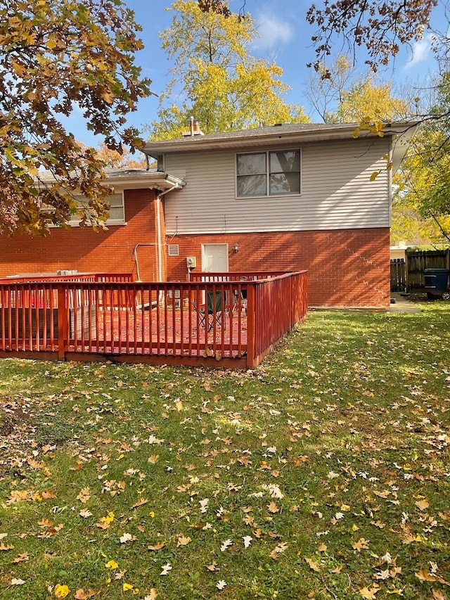 back of property featuring a wooden deck and a yard