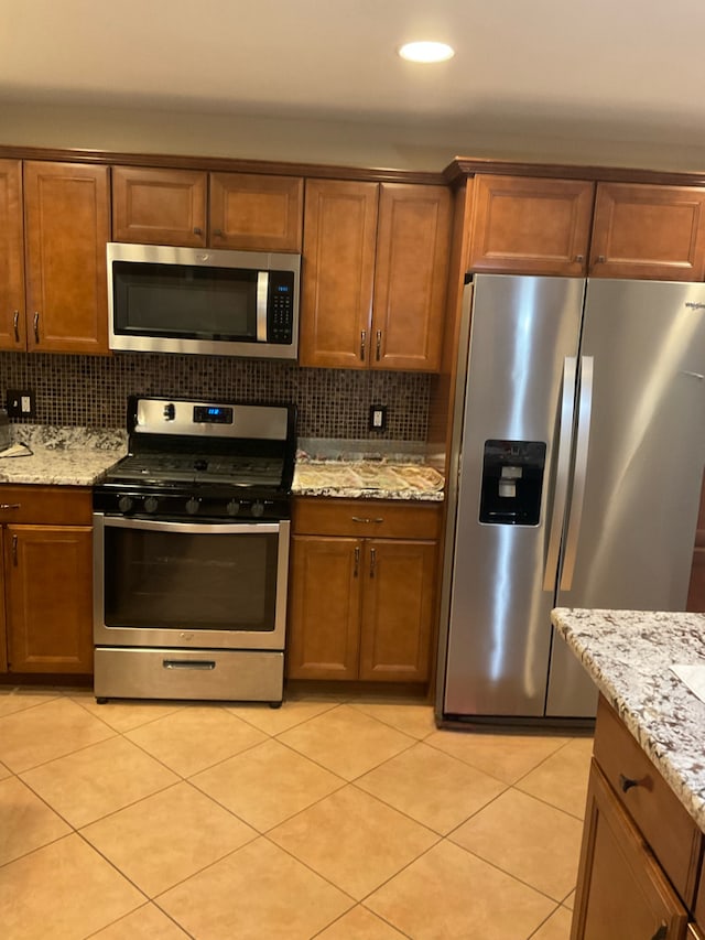 kitchen featuring light stone counters, tasteful backsplash, appliances with stainless steel finishes, and light tile patterned floors