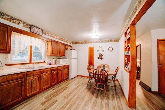 kitchen featuring white appliances, light hardwood / wood-style floors, and sink