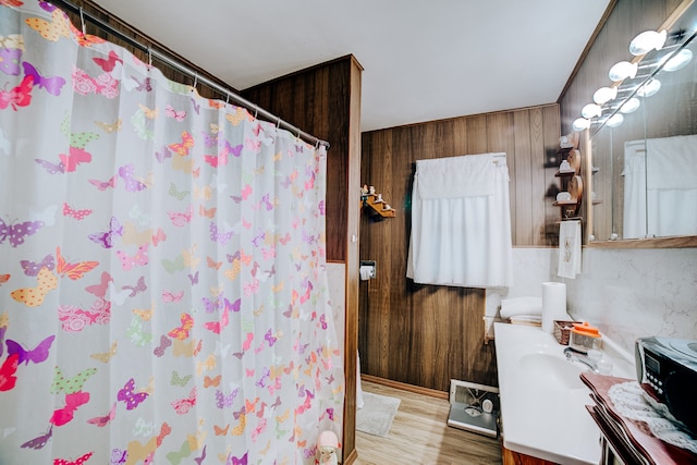 bathroom featuring vanity, wooden walls, curtained shower, and hardwood / wood-style flooring