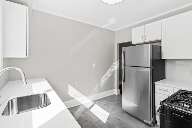 kitchen featuring sink, decorative backsplash, white cabinets, black range with gas cooktop, and stainless steel refrigerator