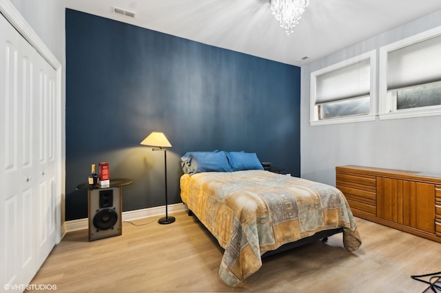 bedroom featuring an inviting chandelier, light hardwood / wood-style floors, and a closet