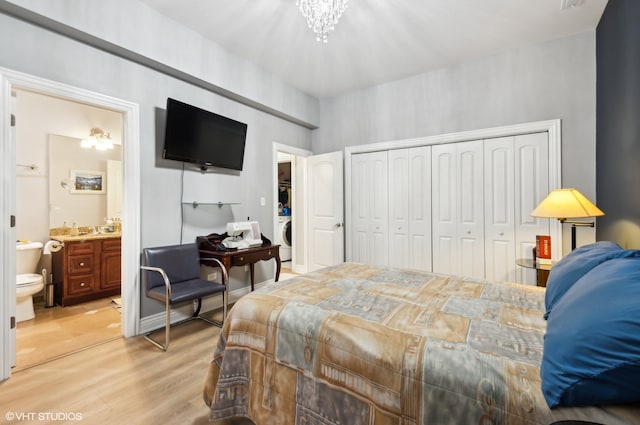 bedroom featuring a closet, washer / dryer, light hardwood / wood-style flooring, an inviting chandelier, and ensuite bathroom