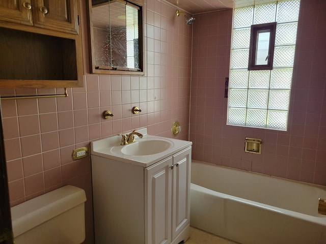 full bathroom featuring vanity, bathtub / shower combination, toilet, and tile walls