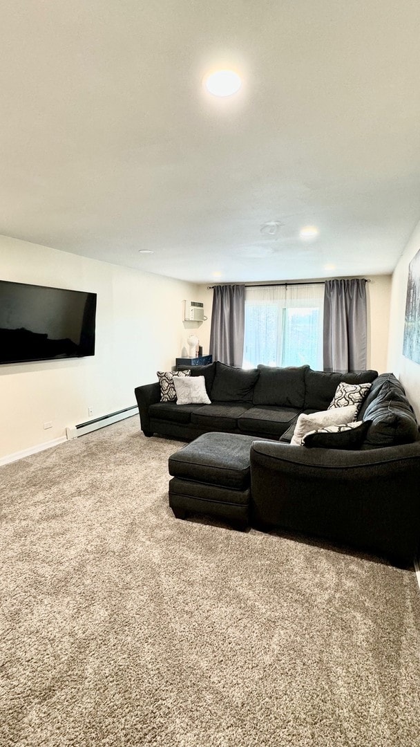 carpeted living room with a wall mounted AC and a baseboard heating unit