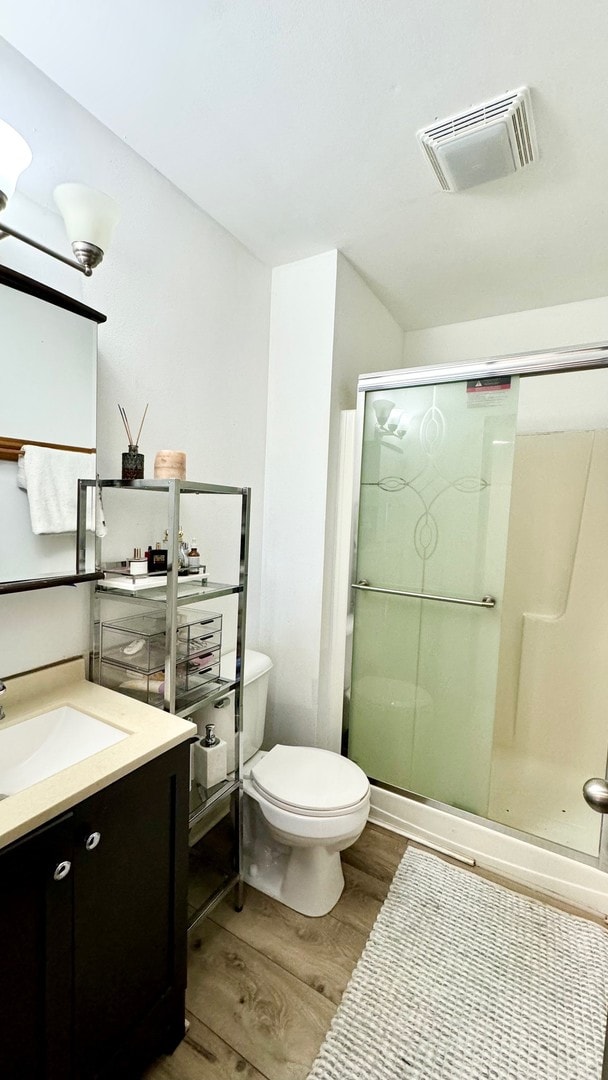 bathroom with vanity, toilet, an enclosed shower, and hardwood / wood-style floors