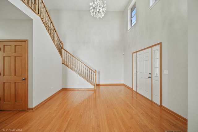 foyer with a towering ceiling, an inviting chandelier, and hardwood / wood-style flooring