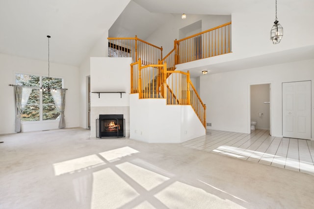 unfurnished living room with a notable chandelier, high vaulted ceiling, carpet floors, and a fireplace