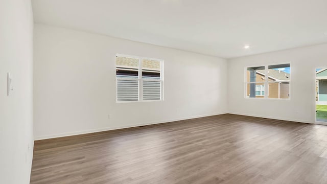 spare room featuring dark wood-type flooring and a healthy amount of sunlight