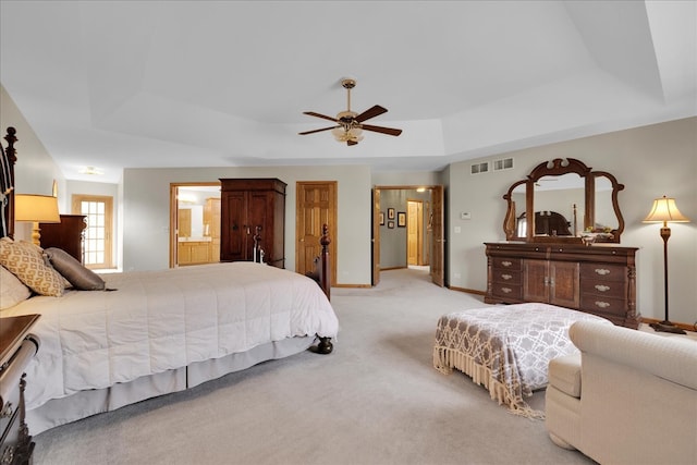 carpeted bedroom featuring connected bathroom, a raised ceiling, and ceiling fan