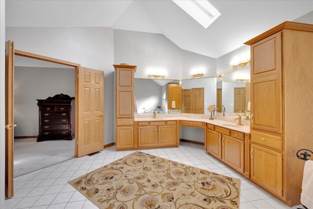 bathroom featuring vanity, vaulted ceiling with skylight, and tile patterned flooring