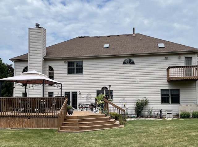 rear view of property with a wooden deck and a lawn