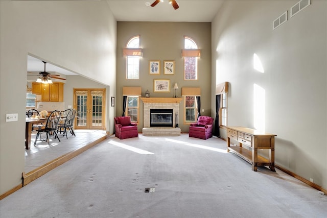 carpeted living room featuring french doors, ceiling fan, and a towering ceiling