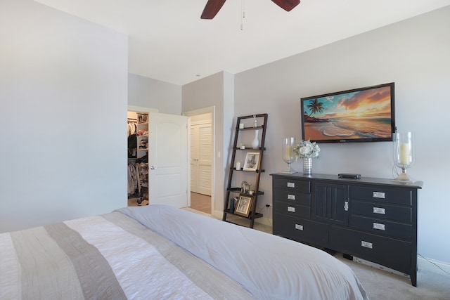 carpeted bedroom featuring a walk in closet, a closet, and ceiling fan