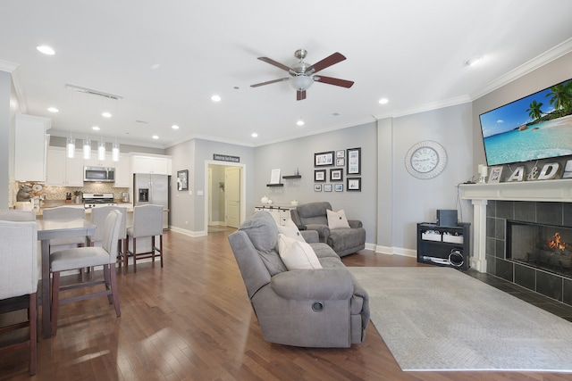 living room featuring ornamental molding, hardwood / wood-style floors, a fireplace, and ceiling fan