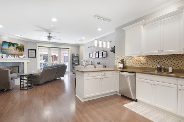 kitchen with light hardwood / wood-style flooring, kitchen peninsula, dishwasher, and white cabinets