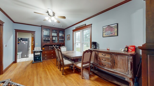 dining space with ceiling fan, crown molding, and light hardwood / wood-style flooring