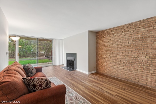 living room featuring hardwood / wood-style flooring, brick wall, and floor to ceiling windows