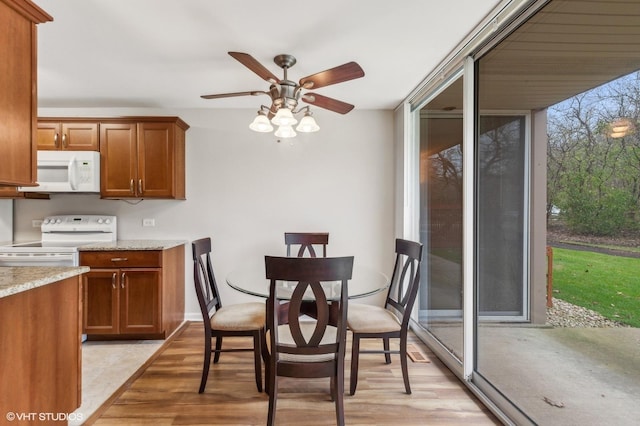 kitchen with ceiling fan, light stone countertops, white appliances, and light hardwood / wood-style floors