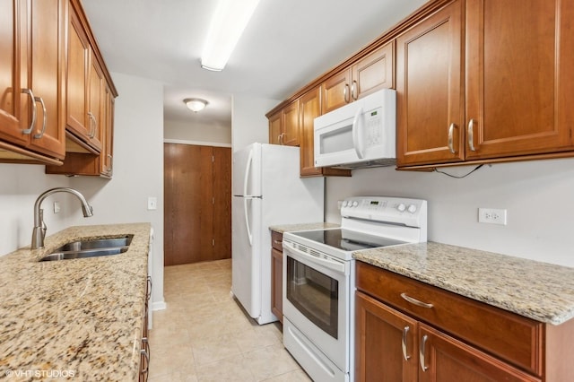 kitchen featuring sink, white appliances, light stone countertops, and light tile patterned floors