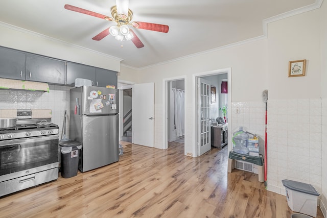 kitchen featuring light wood-type flooring, ceiling fan, stainless steel appliances, tile walls, and crown molding