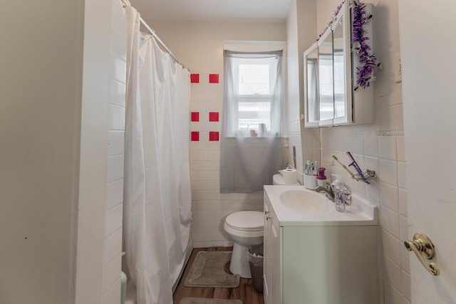 full bathroom with hardwood / wood-style floors, tile walls, shower / bath combo with shower curtain, toilet, and vanity