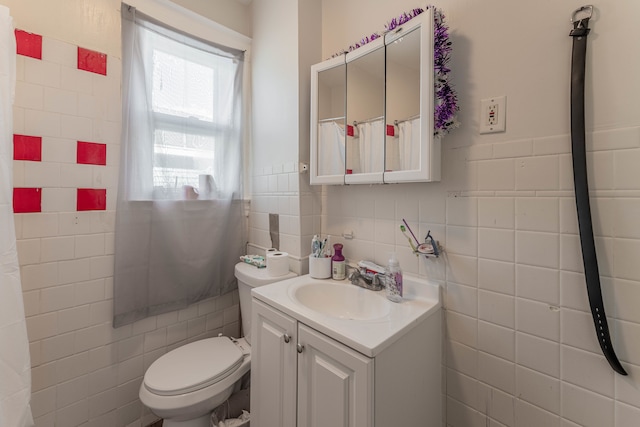 bathroom with vanity, toilet, and tile walls