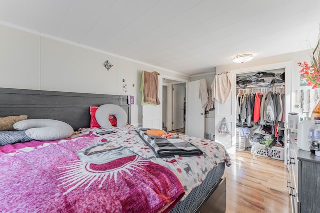 bedroom with light hardwood / wood-style floors, a closet, and ornamental molding