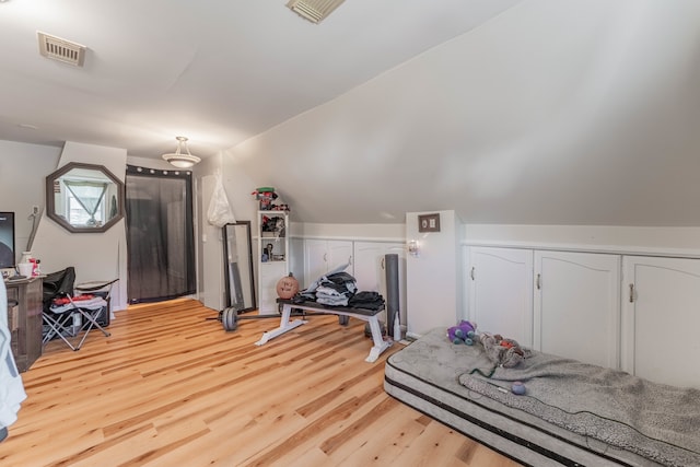 exercise room with lofted ceiling and light hardwood / wood-style flooring