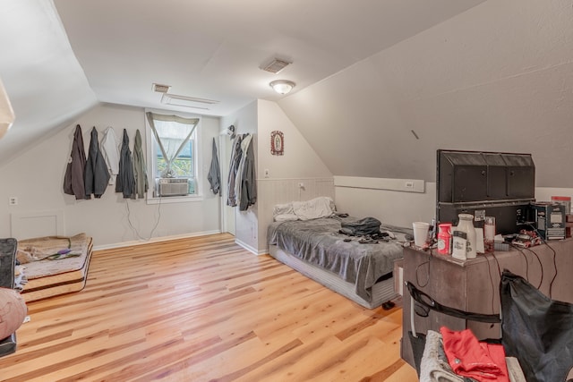 bedroom with cooling unit, light wood-type flooring, and vaulted ceiling