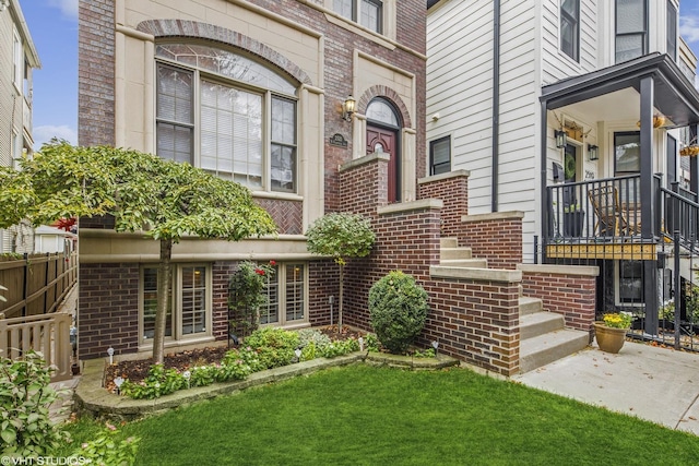 entrance to property featuring a yard, fence, and brick siding