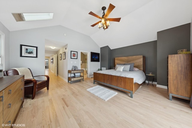 bedroom with ensuite bath, light hardwood / wood-style flooring, ceiling fan, and lofted ceiling with skylight