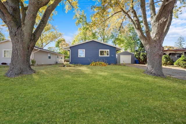 ranch-style home with a garage, a front lawn, and an outbuilding