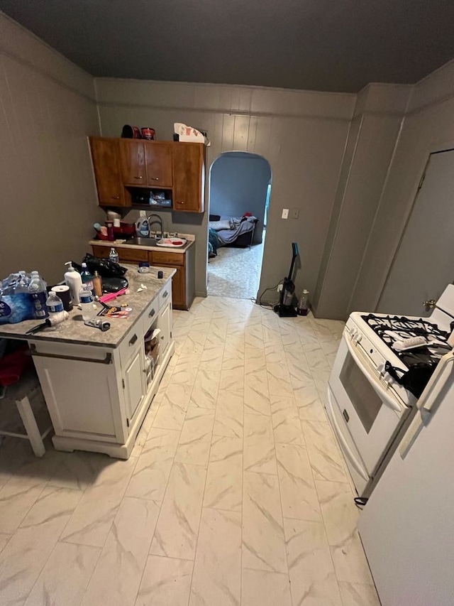 kitchen with white cabinetry, white gas stove, and sink