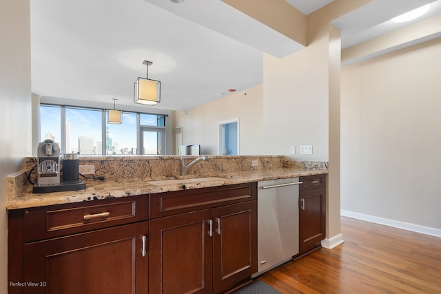 kitchen featuring pendant lighting, light stone counters, stainless steel dishwasher, and hardwood / wood-style floors