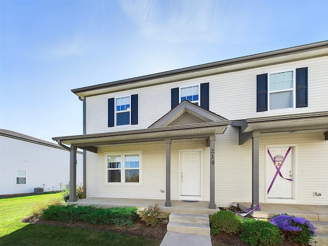 view of front of property with covered porch, central AC, and a front lawn