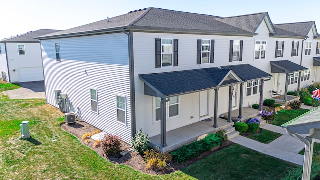 view of front of house with a porch, a front yard, central AC, and a garage