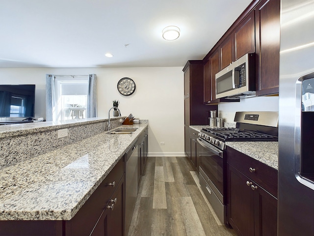 kitchen featuring dark wood-type flooring, light stone countertops, appliances with stainless steel finishes, and sink