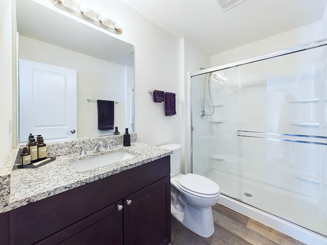 bathroom featuring toilet, hardwood / wood-style floors, vanity, and a shower with door