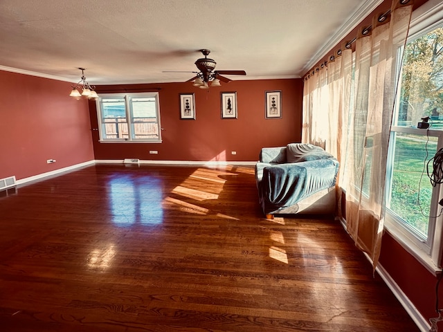 interior space with ceiling fan with notable chandelier, dark hardwood / wood-style flooring, crown molding, and a healthy amount of sunlight