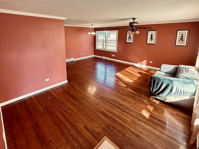 empty room featuring ceiling fan with notable chandelier, crown molding, and dark wood-type flooring