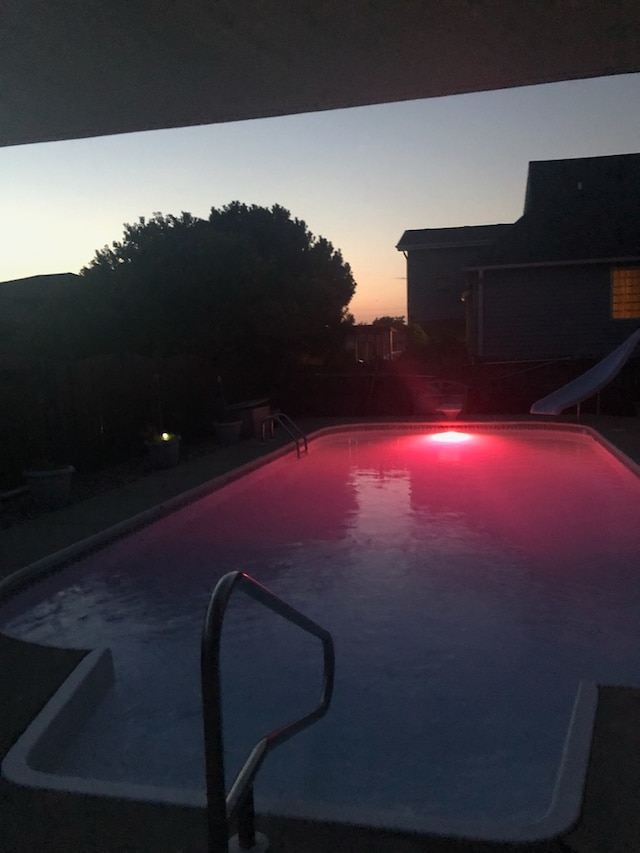 pool at dusk featuring a water slide